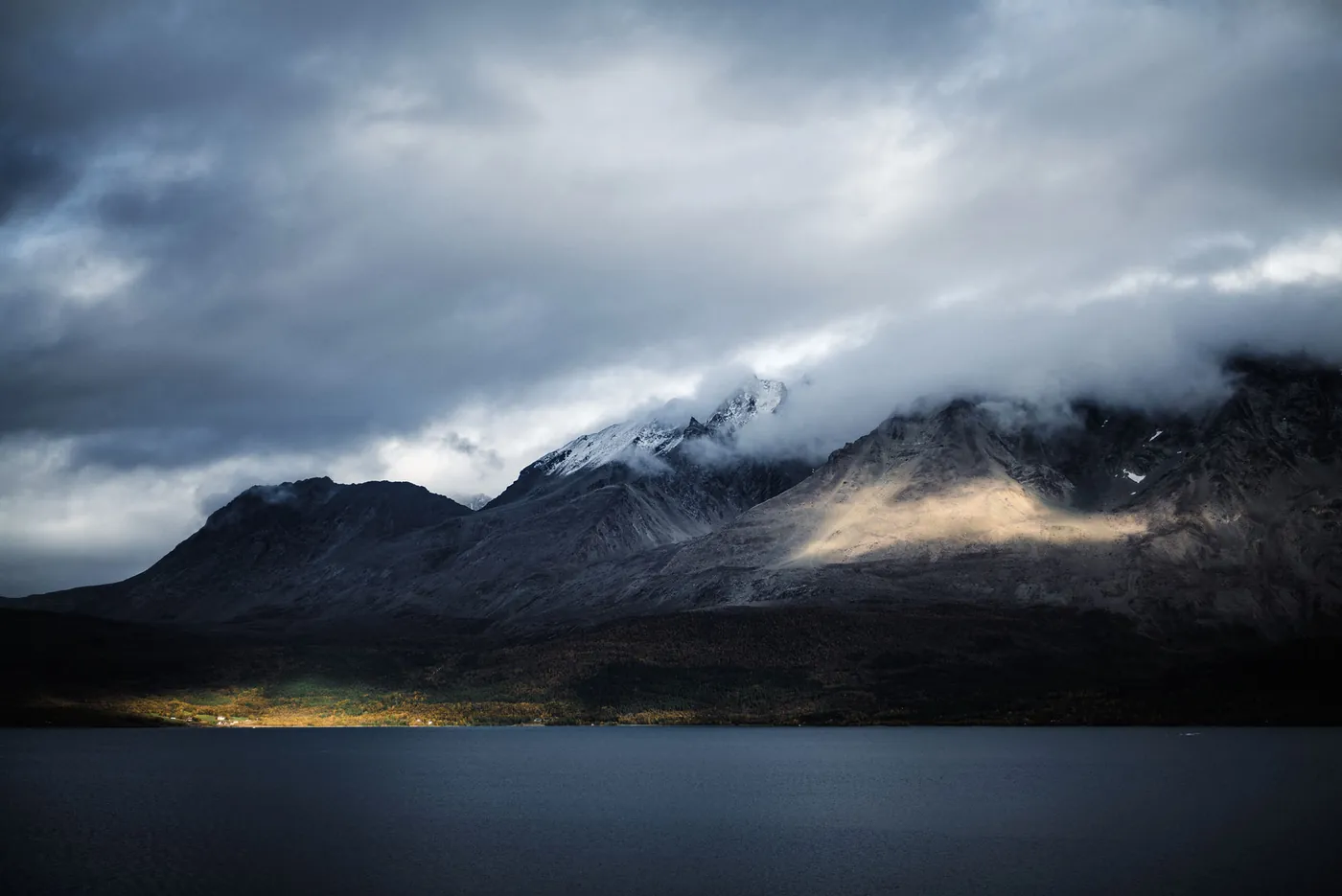Dark clouds over the mountains, a streak of light on the slope